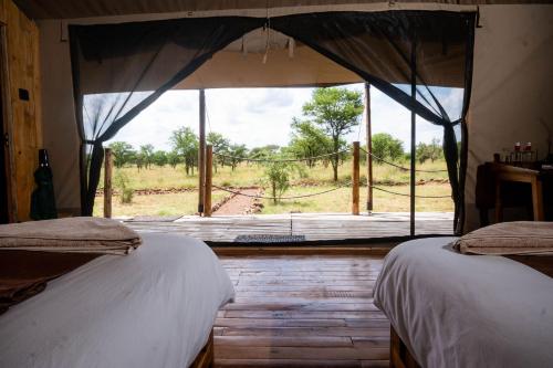 a bedroom with two beds and a window with a view at Serengeti Kifaru Tented Lodge in Mugumu
