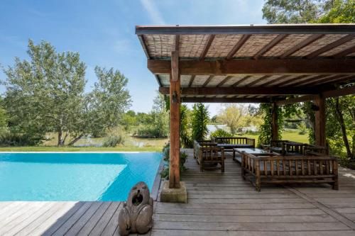 une terrasse en bois avec une pergola à côté d'une piscine dans l'établissement Souvenirs Intemporels, à Arles
