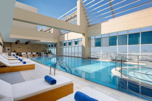 a swimming pool in a building with a view at Grand Millennium Al Wahda Hotel and Executive Apartments Abu Dhabi in Abu Dhabi
