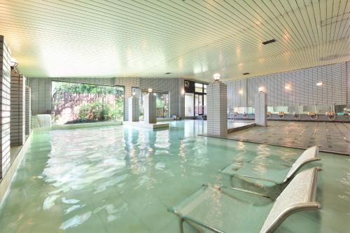 a swimming pool with a chair in a building at Yunogo Onsen HOTEL YUNOMORI BISYUNKAKU in Mimasaka