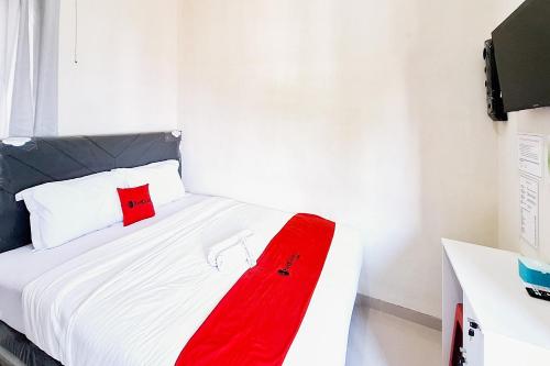 a white bed with a red blanket on it at RedDoorz near Malang Creative Center in Blimbing