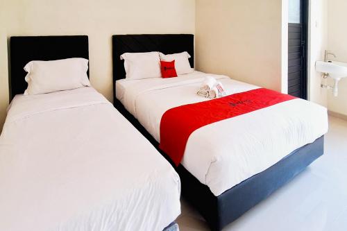 two beds sitting next to each other in a room at RedDoorz near Malang Creative Center in Blimbing