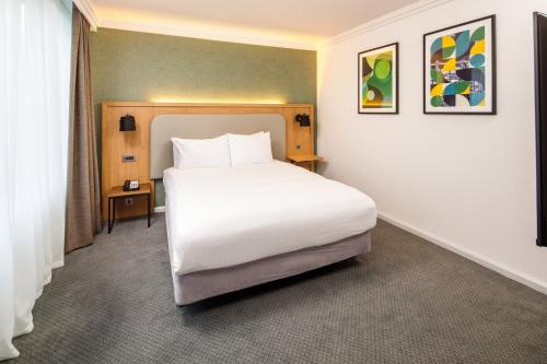 a bedroom with a large white bed in a room at Holiday Inn Milton Keynes Central by IHG in Milton Keynes
