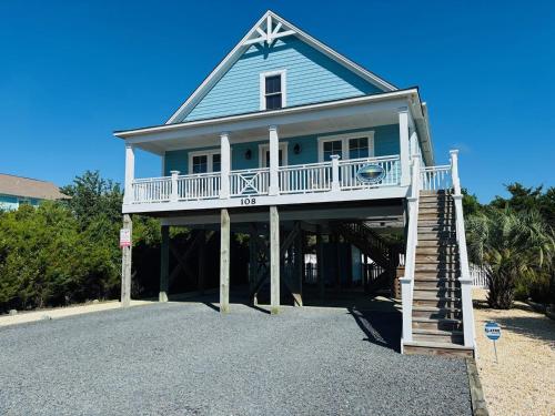a blue house with a balcony and a staircase at Blue Sunset in Holden Beach