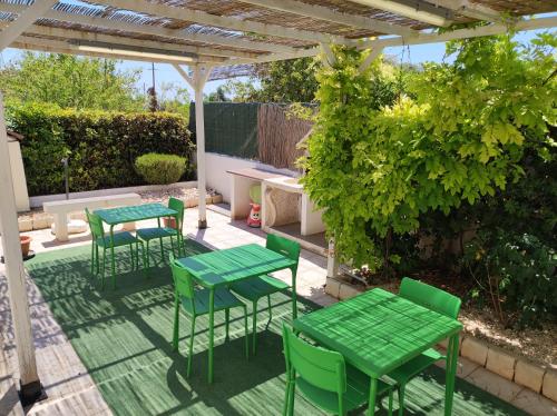 a patio with green tables and chairs under a pergola at B&B AMURI RANNI in Avola
