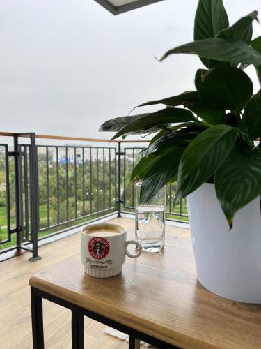 a cup of coffee on a wooden table with a plant at Scandinavian Style Apartment in Fergana