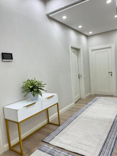 a white room with a table and a potted plant at Scandinavian Style Apartment in Fergana