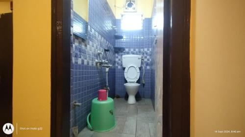 a bathroom with a toilet in a blue tiled stall at Hotel Cosy Inn in Digha