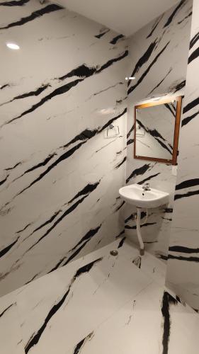 a bathroom with a white sink and a marble wall at Hotel Cosy Inn in Digha