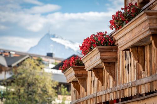 a balcony with red flowers on a building at Kinkara Lodge by Apartment Managers in Kirchberg in Tirol