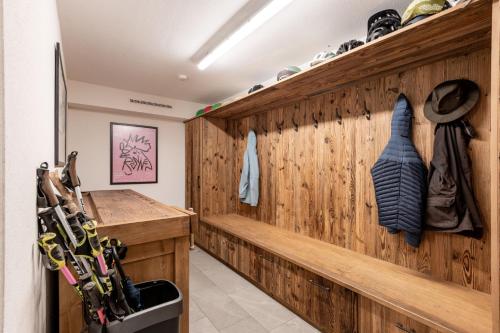 a room with a wooden wall with a bench andweapons at Kinkara Lodge by Apartment Managers in Kirchberg in Tirol
