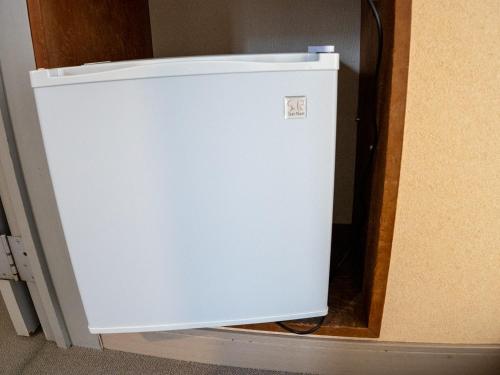 a small white refrigerator sitting in a room at 手打ちそばの宿 石田屋 in Togari
