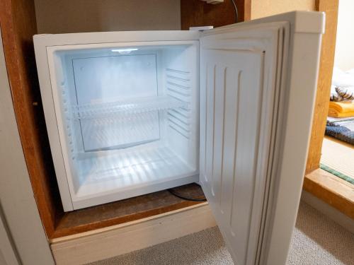an empty refrigerator with its door open in a room at 手打ちそばの宿 石田屋 in Togari