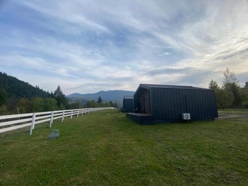 a black building in a field next to a fence at Красник Хілс in Krasnik