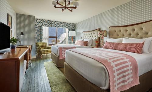 a hotel room with two beds and a television at Graduate by Hilton Bloomington in Bloomington