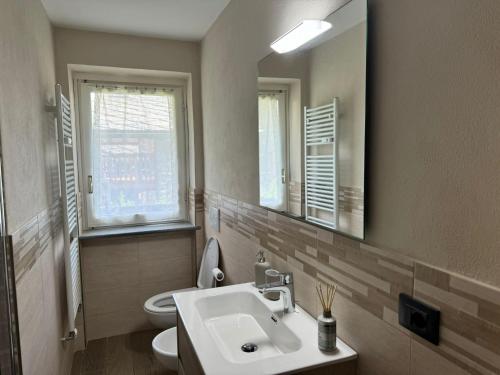 a bathroom with a sink and a toilet and a mirror at CentroCourma e Parcheggio e TopView in Courmayeur