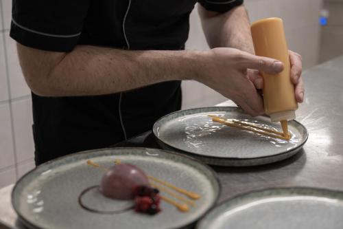 a man holding a knife next to two plates with food at Hotel Riedl in Kössen