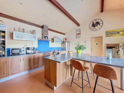 une cuisine avec un comptoir et deux tabourets de bar dans l'établissement L'escapade, à Les Olmes