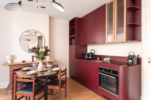 une cuisine avec des placards rouges et une table avec des chaises dans l'établissement L'Opale - Plage de Dinard à 5min à pied, à Dinard