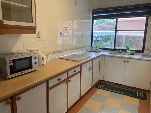 a kitchen with a microwave on a counter with a window at Brinchang Cameron 2R2B 10 paxs KeaFarm #14402 in Brinchang