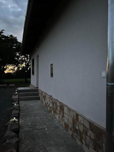 a white building with a window and a brick wall at GABE Vendègház in Gyöngyöstarján