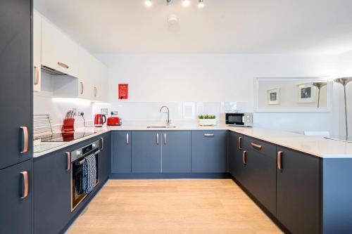 a kitchen with blue cabinets and white counter tops at Roomspace Serviced Apartments - Walton Court in Hersham