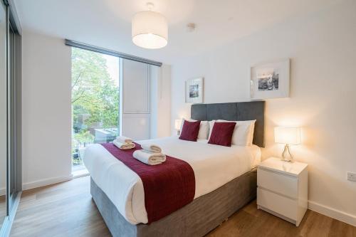 Un dormitorio con una cama grande y una ventana grande. en Roomspace Serviced Apartments - Walton Court, en Hersham
