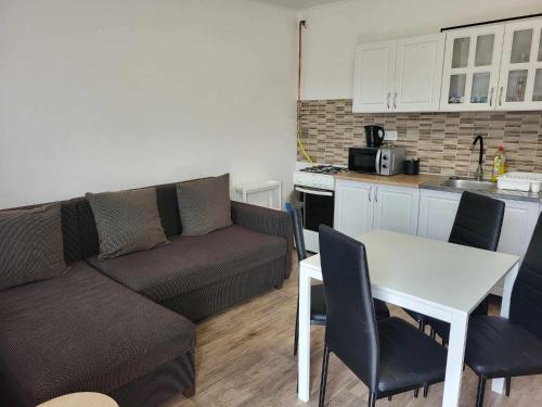 a living room with a couch and a table and a kitchen at GABE Vendègház in Gyöngyöstarján