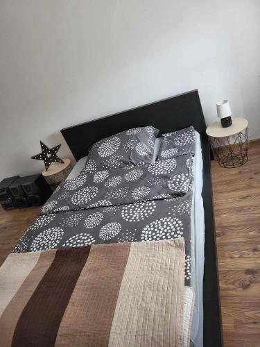 a bedroom with a bed with a black and white comforter at GABE Vendègház in Gyöngyöstarján