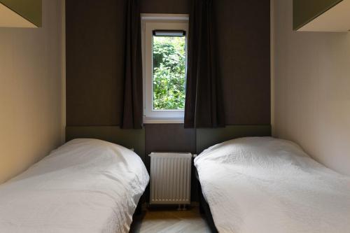 two beds in a room with a window at Luxe vakantiechalet met royale tuin op de Veluwe in Epe