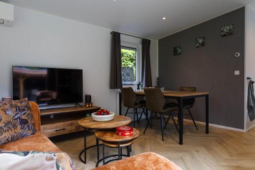 a living room with a couch and a table at Luxe vakantiechalet met royale tuin op de Veluwe in Epe