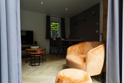 a living room with a chair and a table at Luxe vakantiechalet met royale tuin op de Veluwe in Epe
