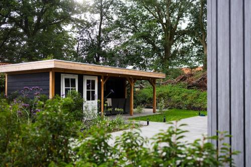 a small shed with a porch in a garden at Luxe vakantiechalet met royale tuin op de Veluwe in Epe