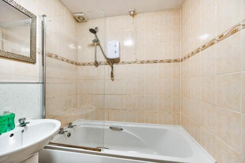 a bathroom with a white tub and a sink at Hopetoun House in Springside