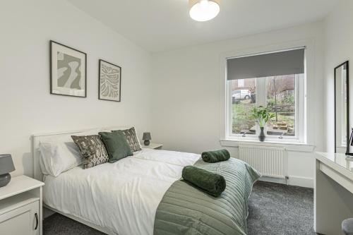 a white bedroom with a bed and a window at Bountrees Apartment in Jedburgh