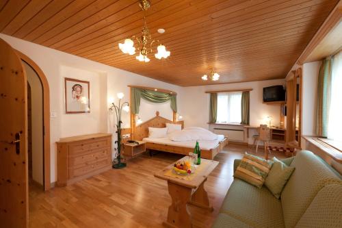 een slaapkamer met een bed, een bank en een tafel bij Hotel Astras in Scuol