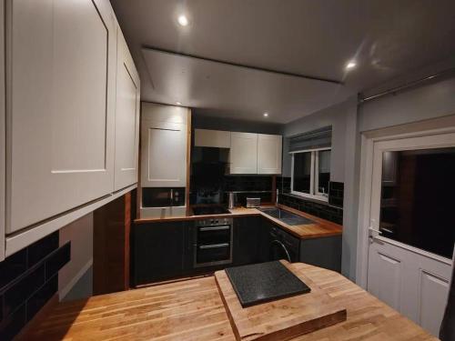 a kitchen with white cabinets and a wooden table at Cozy Blackpool Retreat with 3 Bedrooms in Blackpool