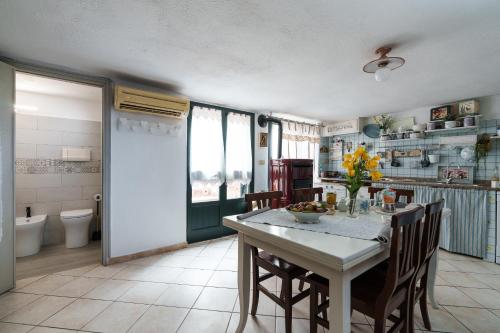 a kitchen with a table and chairs and a bathroom at Sa Dommo de Luigi in Orosei