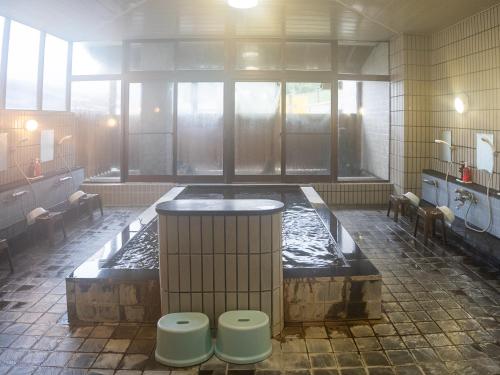 a bathroom with a hot tub in the middle of a room at 手打ちそばの宿 石田屋 in Togari