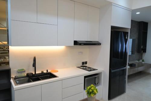 a kitchen with white cabinets and a black refrigerator at Apartment Medan Podomoro City Deli by OLS Studio in Medan