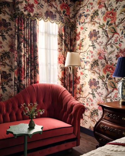 a red couch in a room with floral wallpaper at Graduate by Hilton Palo Alto in Palo Alto