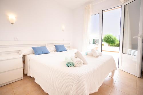 a white bedroom with two beds with towels on them at Apartamentos Annabel's I in Cala Galdana