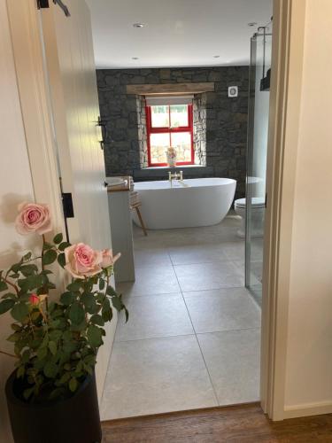 a bathroom with a white bath tub and a sink and a bathroom with roses at Farm Stay at THE GLEBE COTTAGE KILREA in Tamlaght