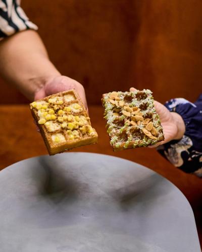 two hands holding two pieces of bread with nuts on it at B Hotel Kuala Lumpur in Kuala Lumpur
