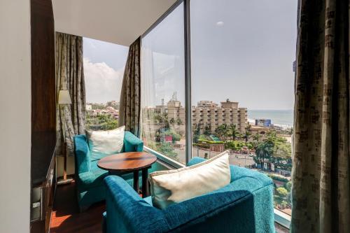 a room with two blue chairs and a large window at Treebo Blak & Wite Rk Beach in Visakhapatnam
