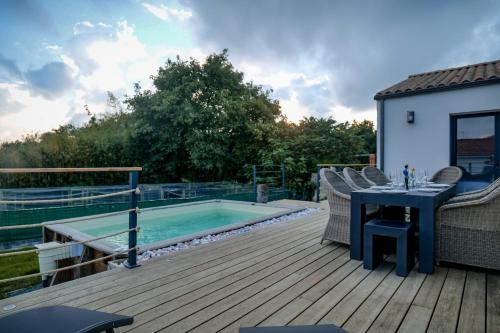 - une terrasse avec une table et des chaises à côté de la piscine dans l'établissement Jolie maison récente avec jardin et piscine Les Sables - 8 personnes, à Les Sables-dʼOlonne