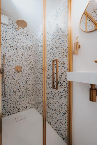 La salle de bains est pourvue d'une douche et de papier peint bleu et blanc. dans l'établissement Doubs Moment, à Serre-lès-Sapins