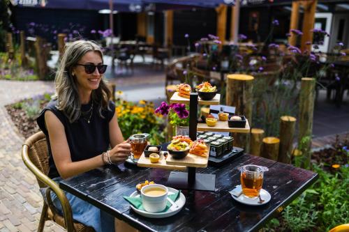 a woman sitting at a table with a tray of food at Luxe vakantiechalet met royale tuin op de Veluwe in Epe