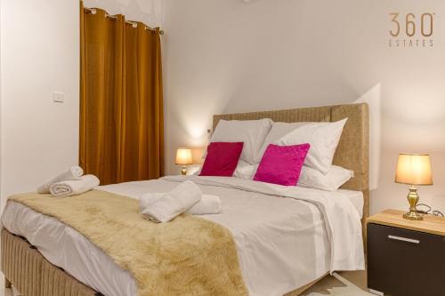 a bedroom with a large white bed with pink pillows at Stunning 2BR Penthouse with terrace in Mosta by 360 Estates in Mosta