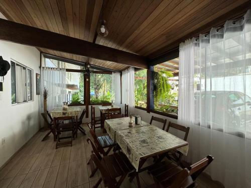 een eetkamer met tafels en stoelen en ramen bij Pousada Rancho do André in Paraty